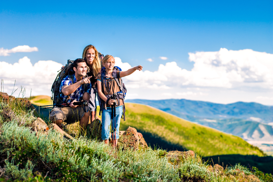 Family on mountain side hiking pointing off into the distance